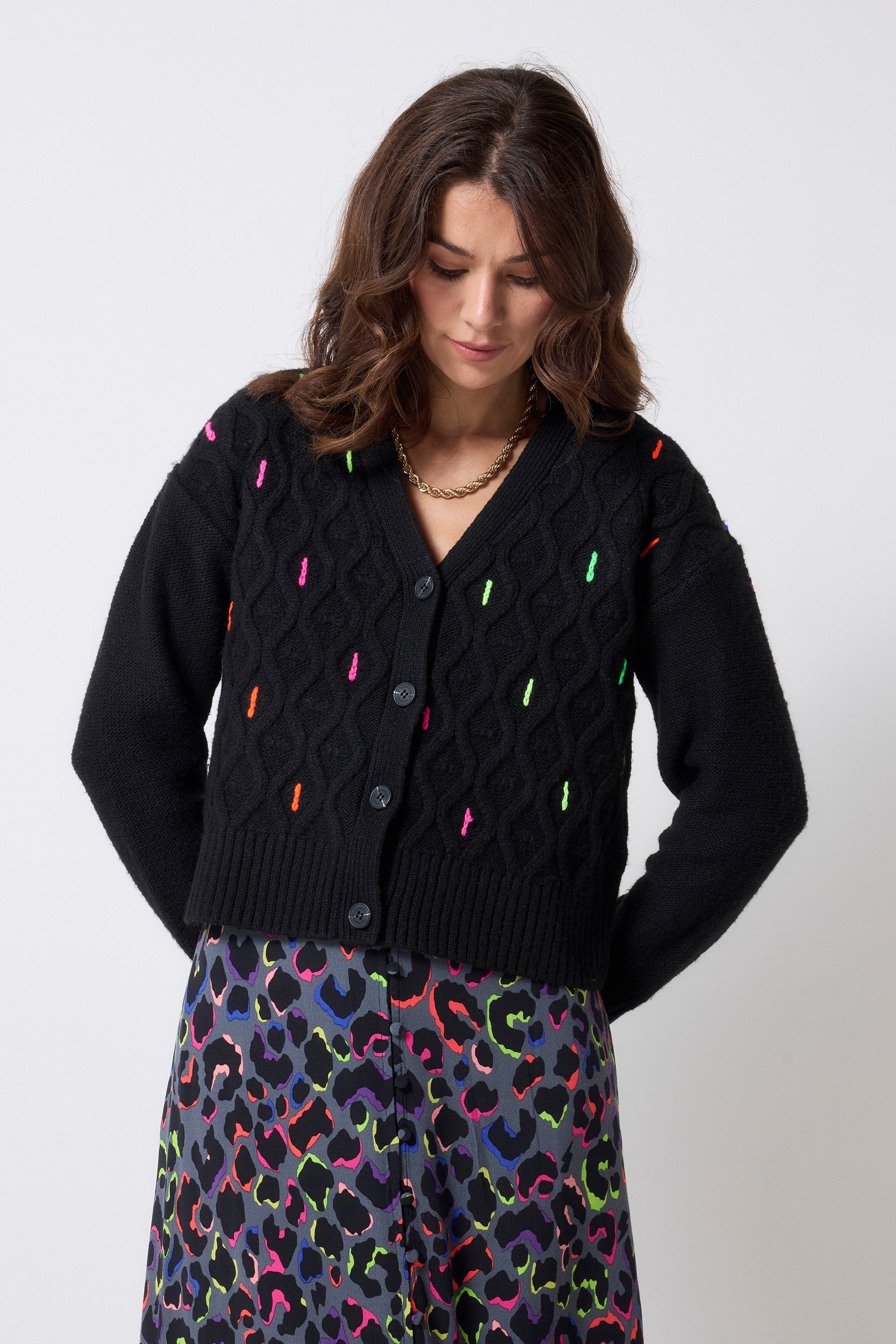 Scamp and Dude Black with Neon Rainbow Flecks Cable Knit Cardigan | Model wearing a grey with rainbow leopard print midi tea dress with a black cardigan that has rainbow fleck detail.