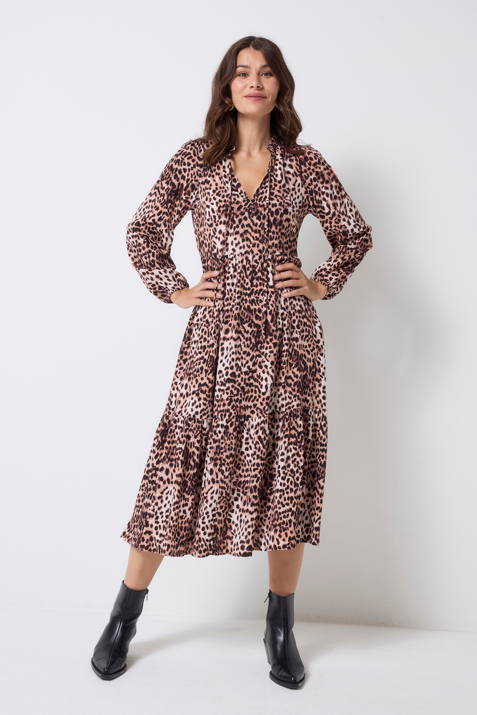 Scamp and Dude Neutral with Black Cheetah Blouson Sleeve Tie Front Midi Dress | Model wearing a neutral with black cheetah tie front midi dress with long sleeves. Worn with black heeled boots.