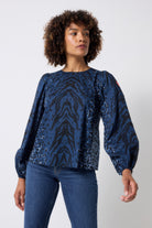 Scamp and Dude Navy with Black Zebra Blouson Sleeve Top | Model wearing a navy long sleeve zebra print top with dark blue jeans.