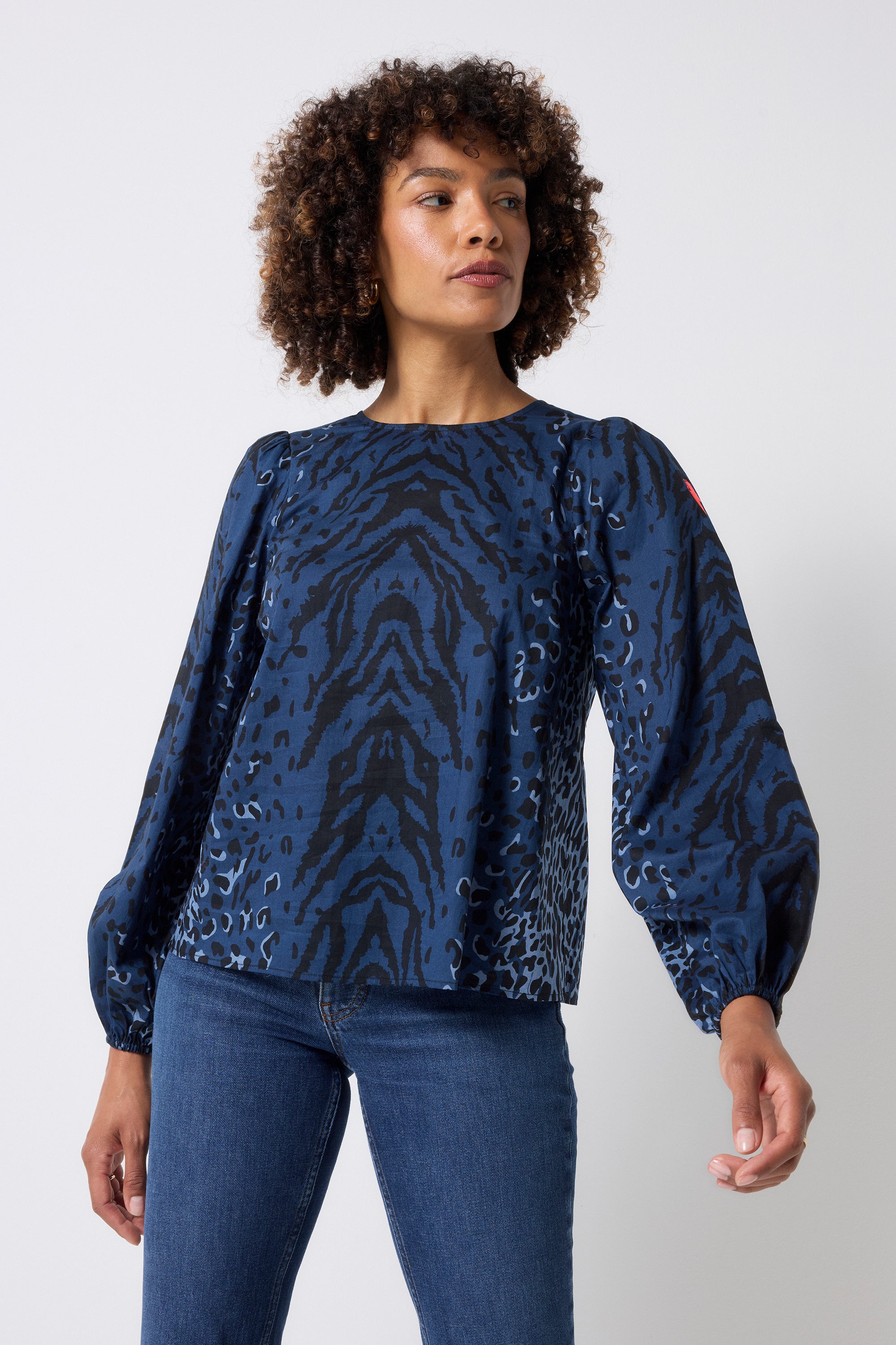 Scamp and Dude Navy with Black Zebra Blouson Sleeve Top | Model wearing a navy long sleeve zebra print top with dark blue jeans.