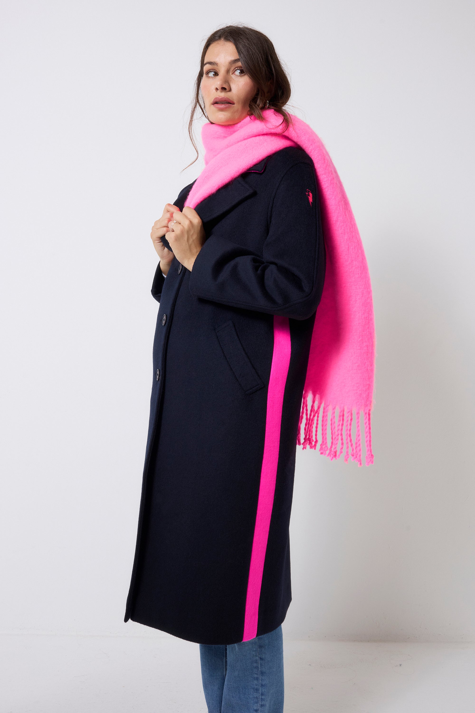 Scamp and Dude Neon Pink Fringe Scarf | Model wearing a navy wool blend coat with blue jeans and a neon pink fringe scarf.