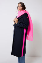 Scamp and Dude Neon Pink Fringe Scarf | Model wearing a navy wool blend coat with blue jeans and a neon pink fringe scarf.