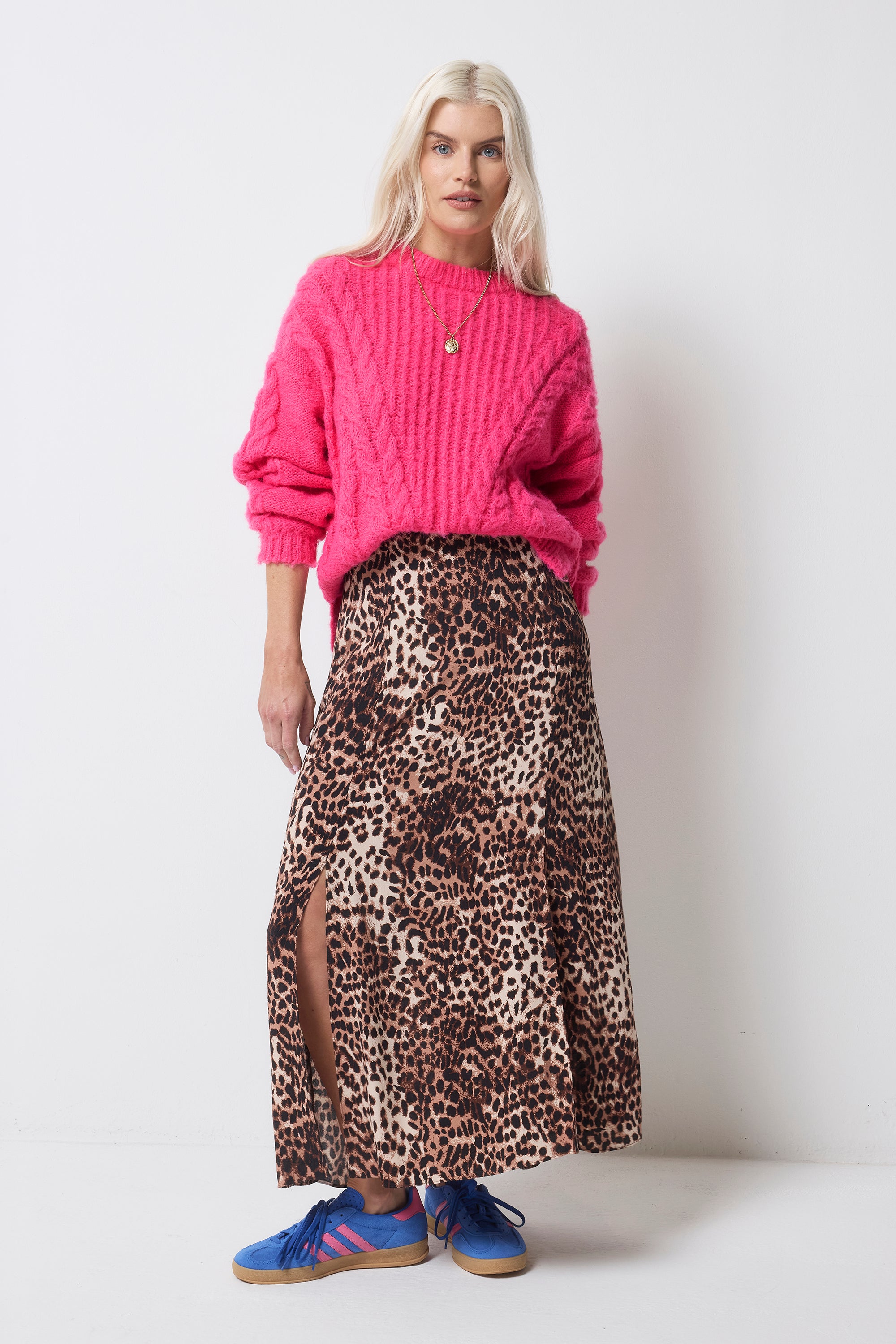 Scamp and Dude Pink Cable Knit Cropped Jumper | Model wearing a neutral cheetah print skirt with a pink cropped knit jumper and blue trainers.