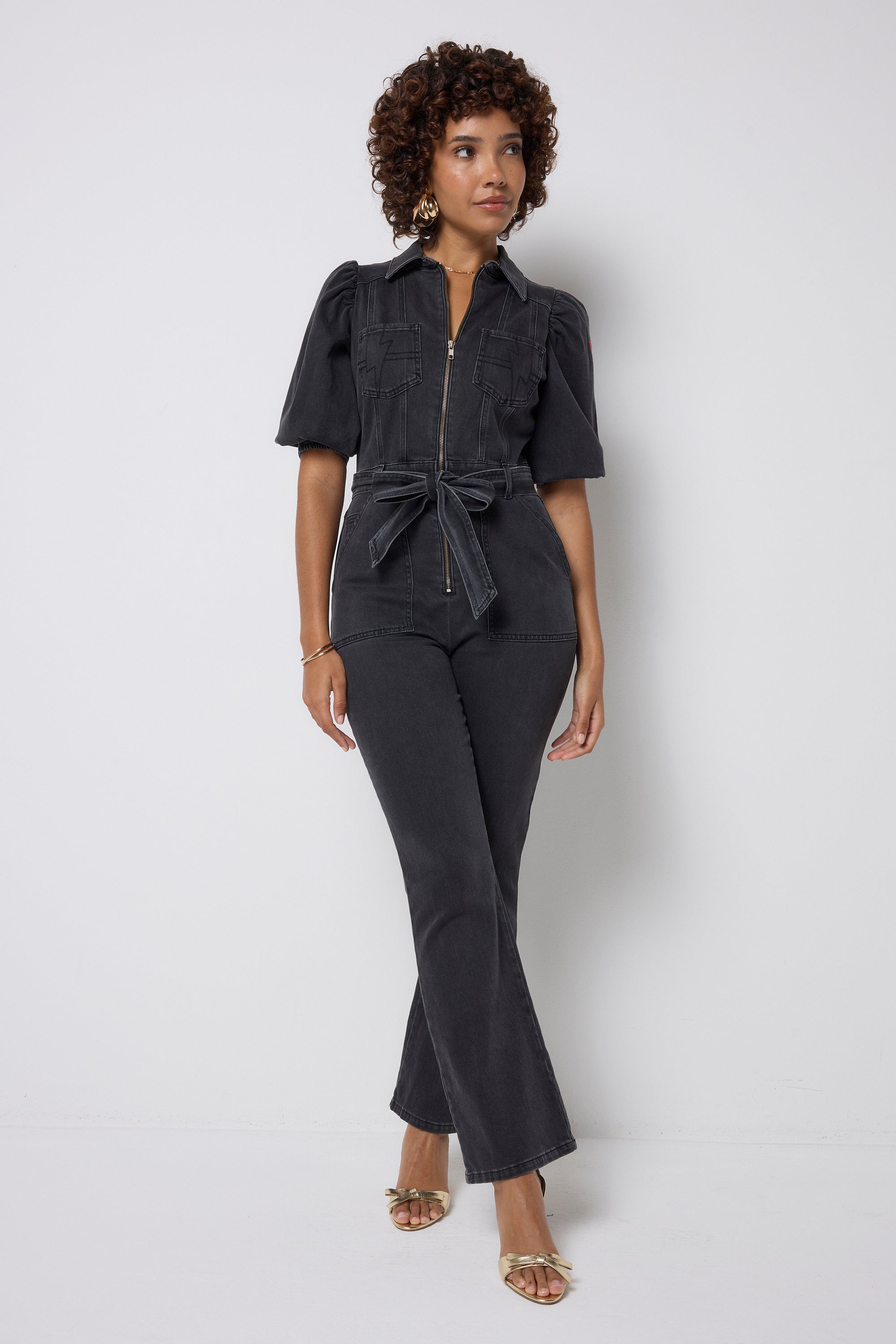 Scamp and Dude Washed Black Denim Wide Leg Jumpsuit | Model wearing a washed black jumpsuit that features a zip front detail and belt.