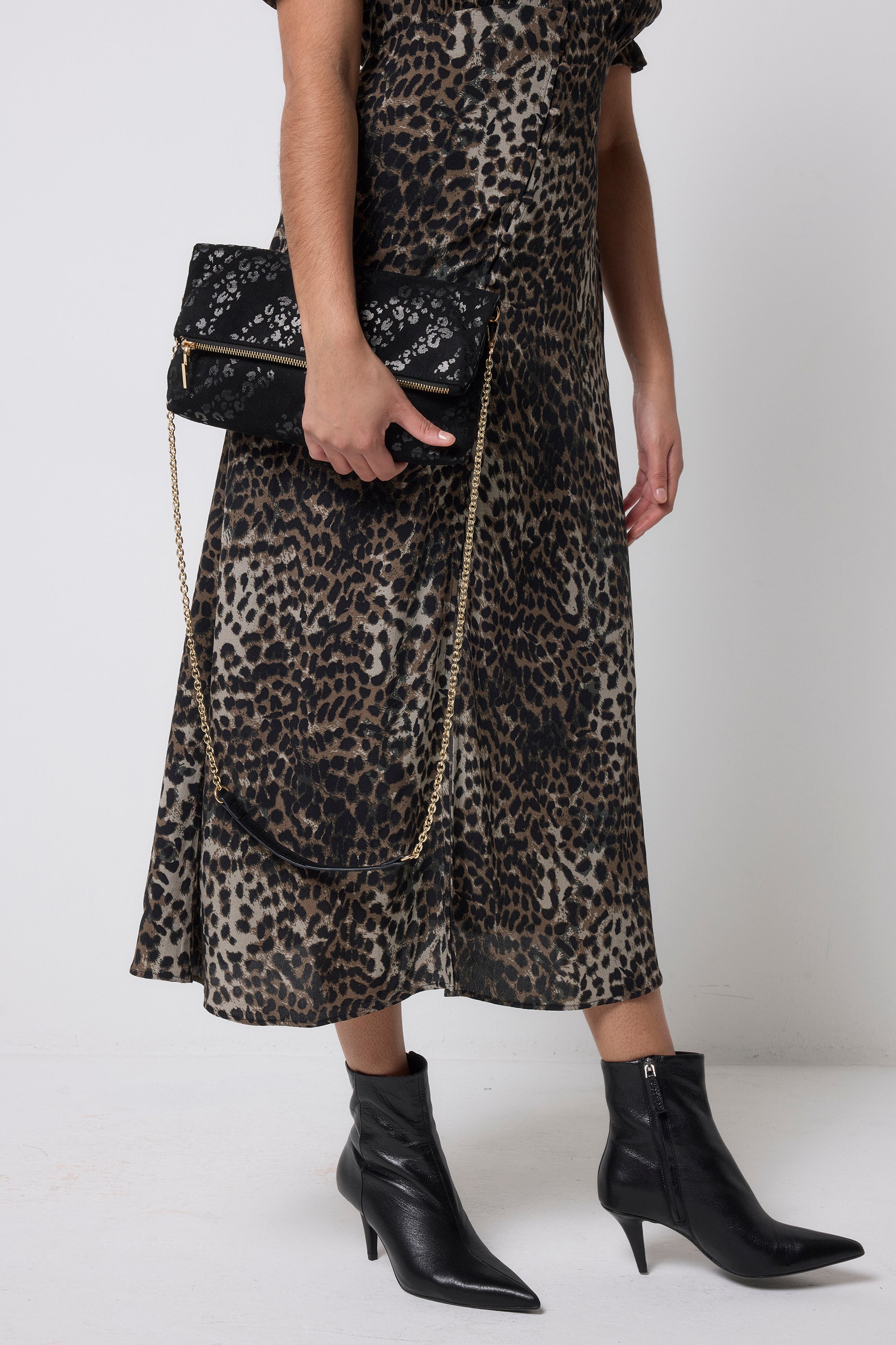 Scamp and Dude Black Leopard Faux Suede Cross Body Bag | Model holding a black leopard bag in a faux suede finish paired with a khaki cheetah print tea dress.