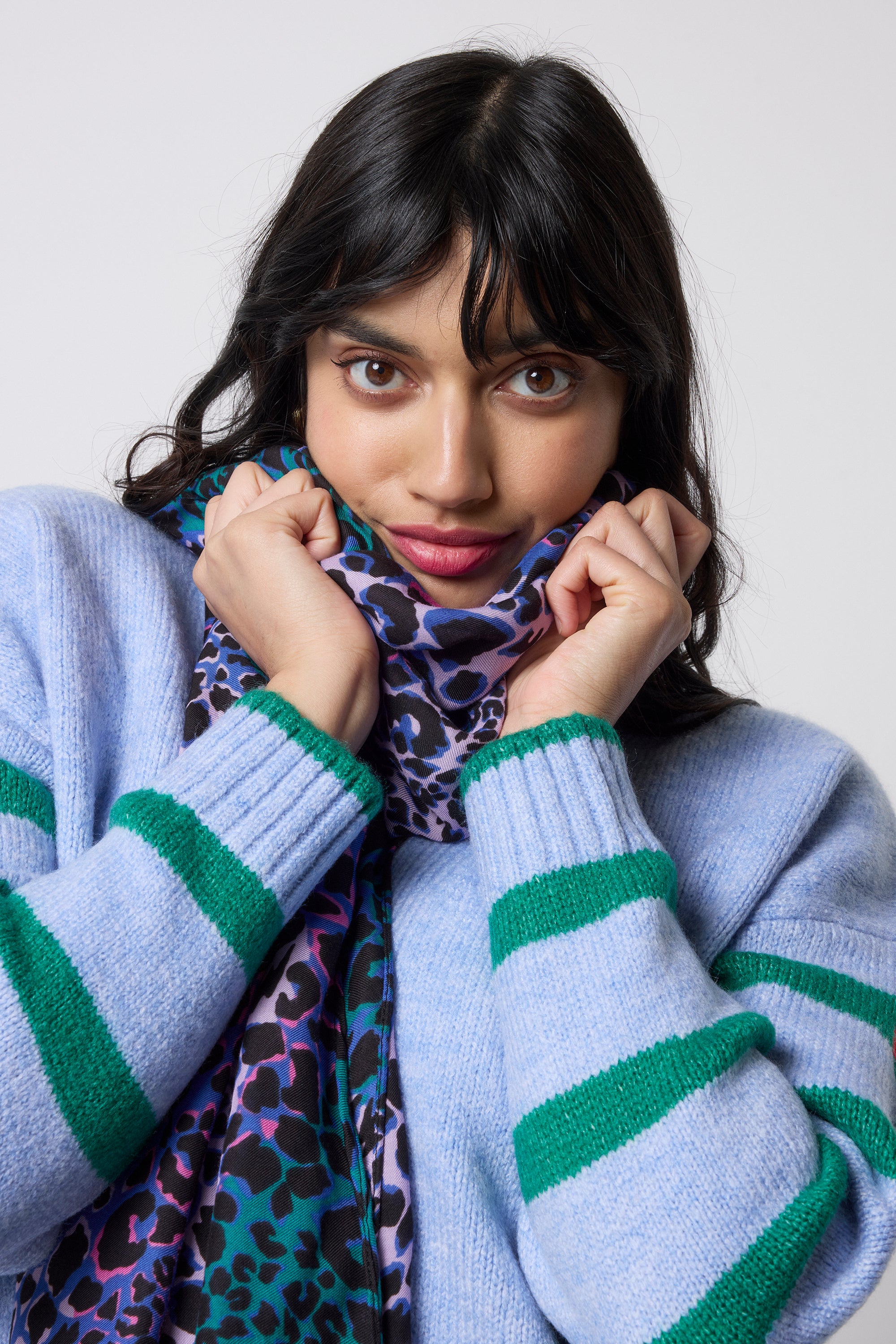 Scamp and Dude Blue with Green and Lilac Spliced Leopard Charity Super Scarf | Model wearing a blue and green striped cardigan with a blue and green spliced print super scarf.