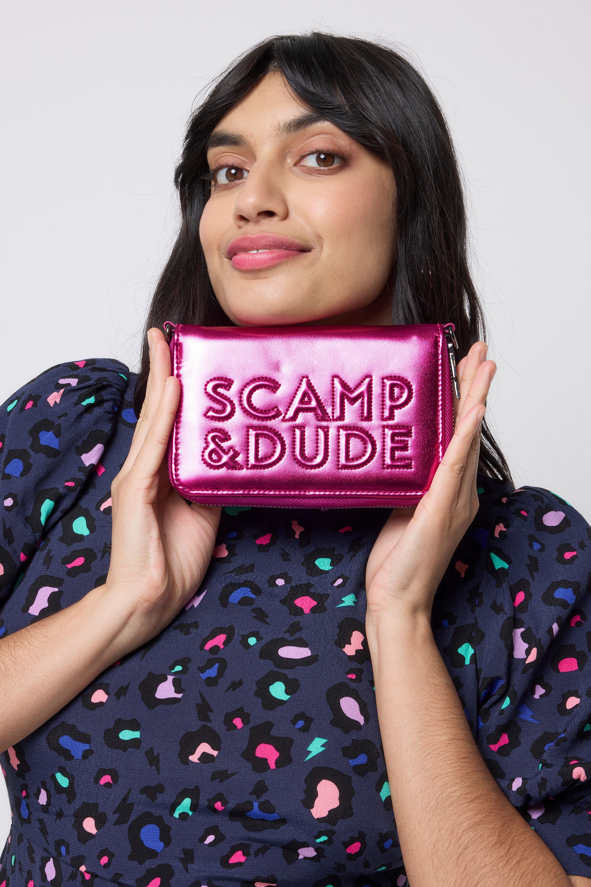 Scamp and Dude Pink Embossed Wallet | Model wearing a navy leopard print dress with a pink embossed wallet.