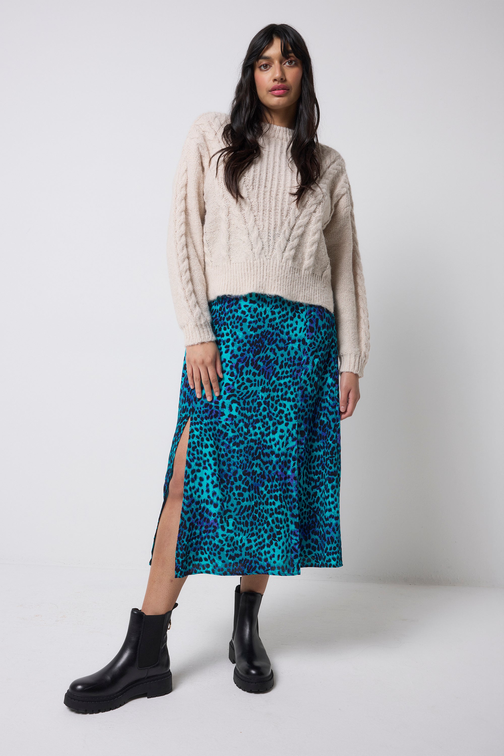 Scamp and Dude Oatmeal Cable Knit Jumper | Model wearing a oatmeal cable knit jumper with a turquoise cheetah print midi skirt and black boots.
