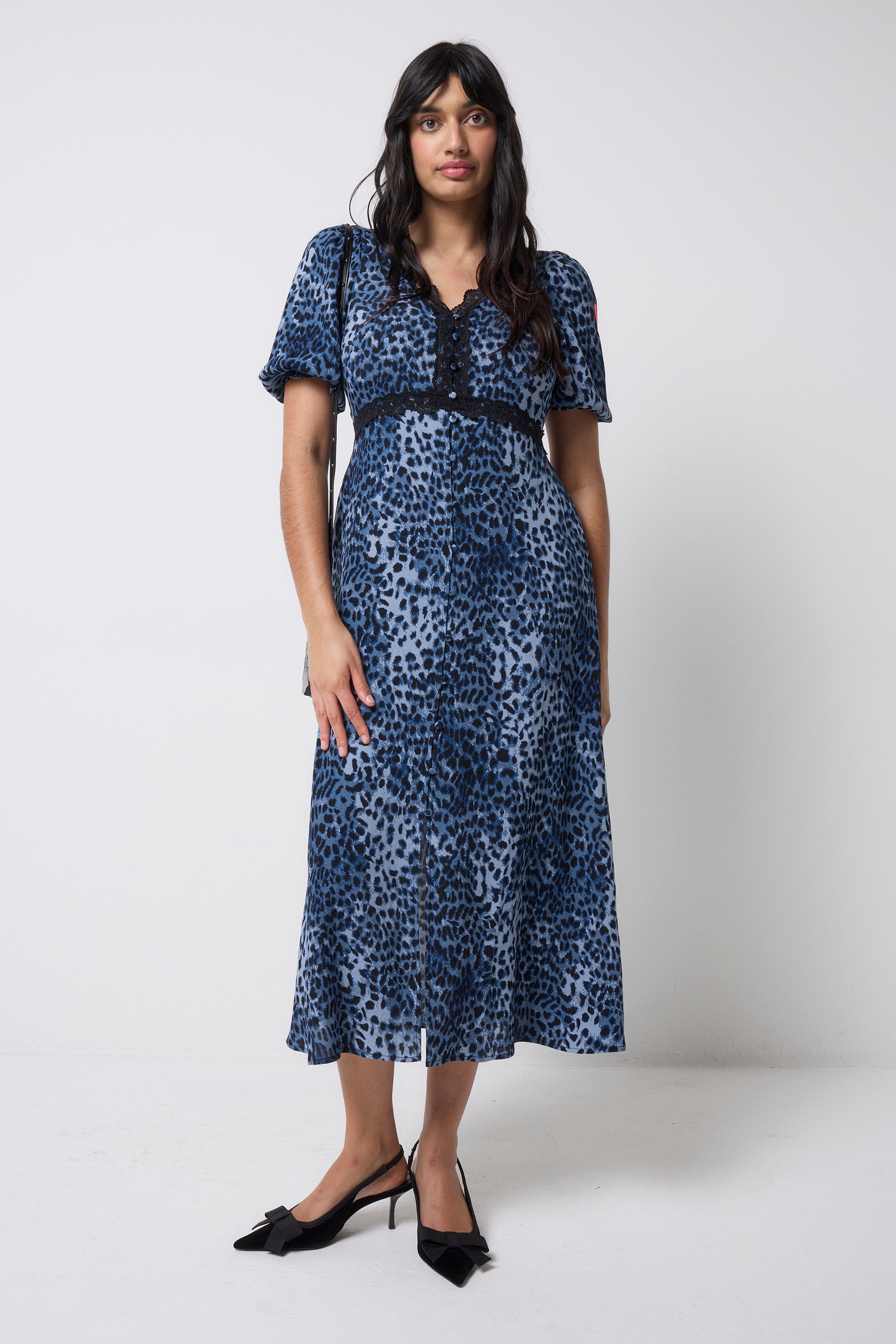Scamp and Dude Navy Cheetah Lace Trim Puff Sleeve Midi Tea Dress | Model wearing a navy cheetah print tea dress featuring lace trim detail. Worn with black bow heels.