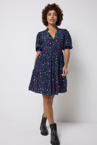 Scamp and Dude Navy with Rainbow Snow Leopard Zip Detail Tiered Short Dress | Model wearing dark navy short dress with zip front detail in a rainbow snow leopard print. Worn with black boots.