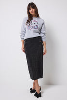 Scamp and Dude Black with Rainbow Lurex Knit Midi Skirt | Model wearing a grey crew neck sweatshirt with a black knitted midi skirt featuring rainbow lurex stripes running through it.