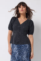 Scamp and Dude Washed Black Button Through Denim Top | Model wearing a black denim button front top with a navy cheetah print midi skirt.