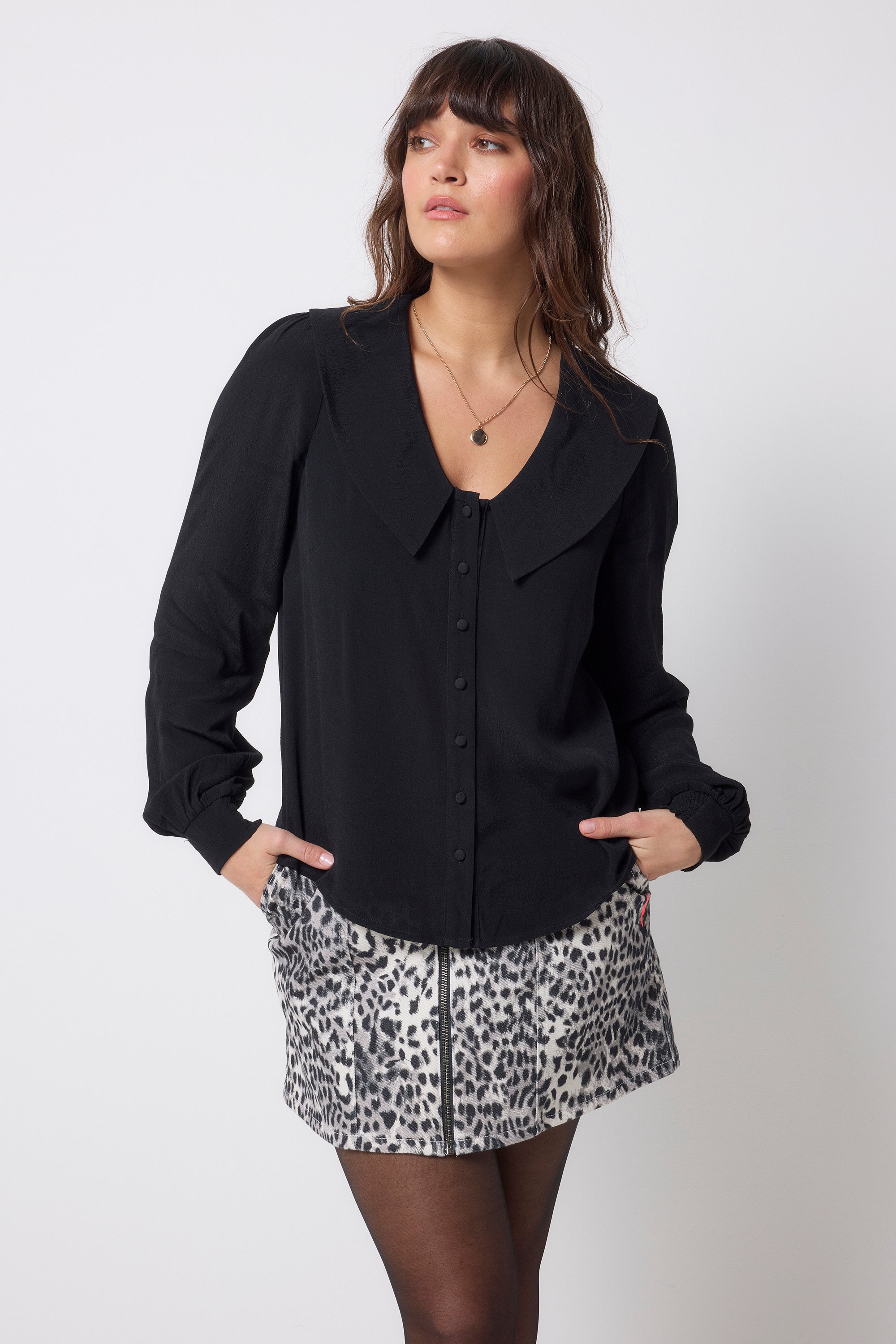 Scamp and Dude Black Collared Blouse | Model wearing a black long sleeve blouse with peter pan collar detail. Worn with a grey cheetah print denim skirt and tights.