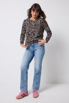 Scamp and Dude Neutral Jaguar Printed Knit Jumper | Model wearing a pair of light blue boyfriend jeans with a neutral jaguar print knit jumper and pink trainers.