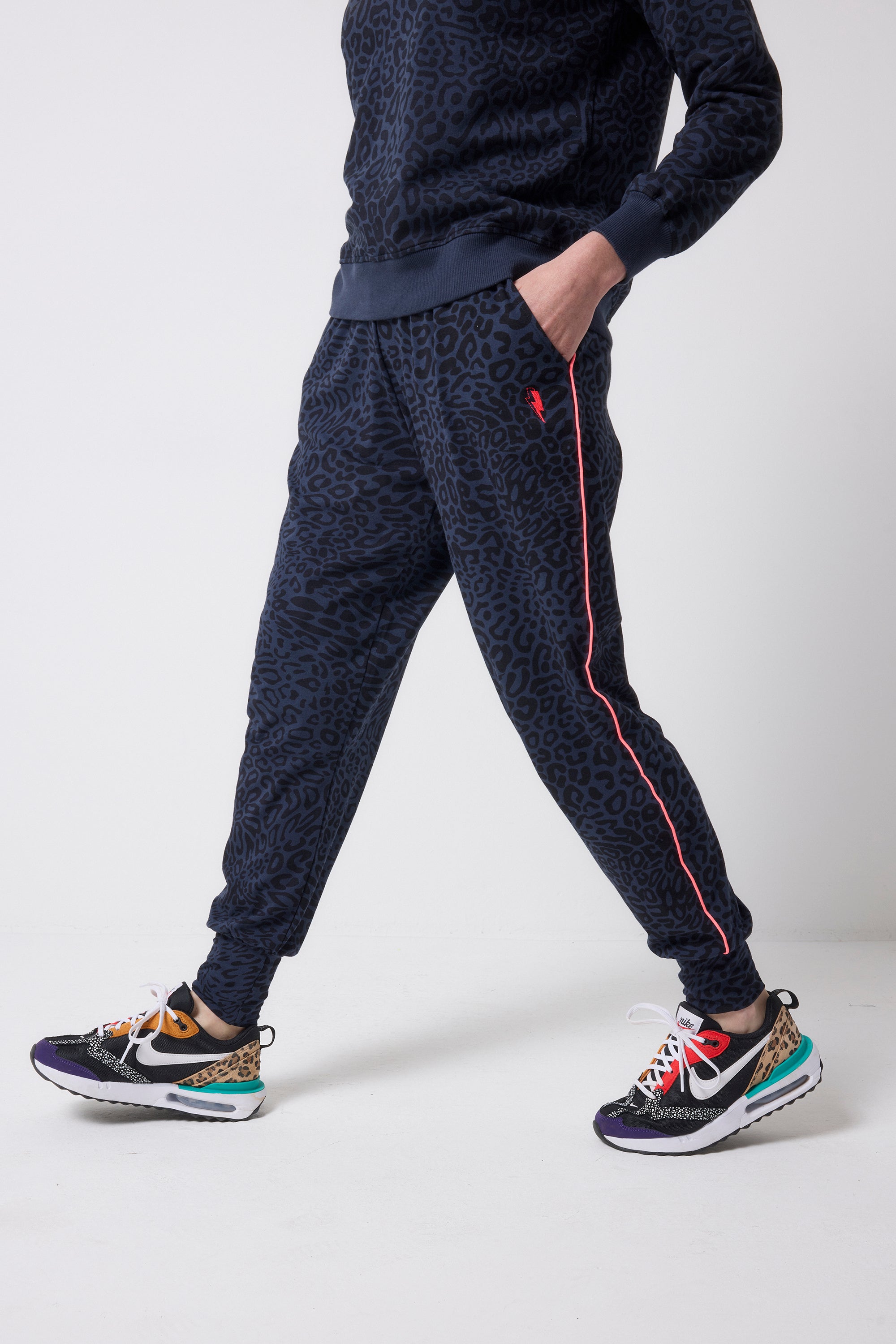 Scamp and Dude Navy with Black Leopard Ray Slouch Joggers | Model wearing navy leopard ray print joggers with a matching sweatshirt and colourful trainers.