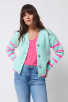 Scamp and Dude Dusty Blue With Neon Pink Stripe Cardigan | Model wearing a pair of light blue jeans with a pink t-shirt and a dusty blue cardigan.