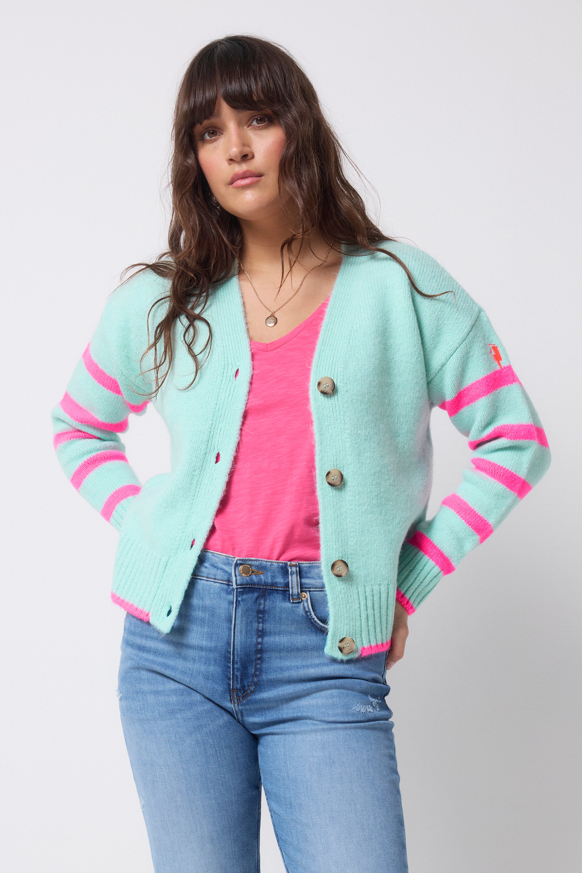 Scamp and Dude Dusty Blue With Neon Pink Stripe Cardigan | Model wearing a pair of light blue jeans with a pink t-shirt and a dusty blue cardigan.