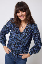 Scamp and Dude Navy Jaguar Collared Blouse | Model wearing a blue jaguar print button front blouse with dark blue jeans against a white background.