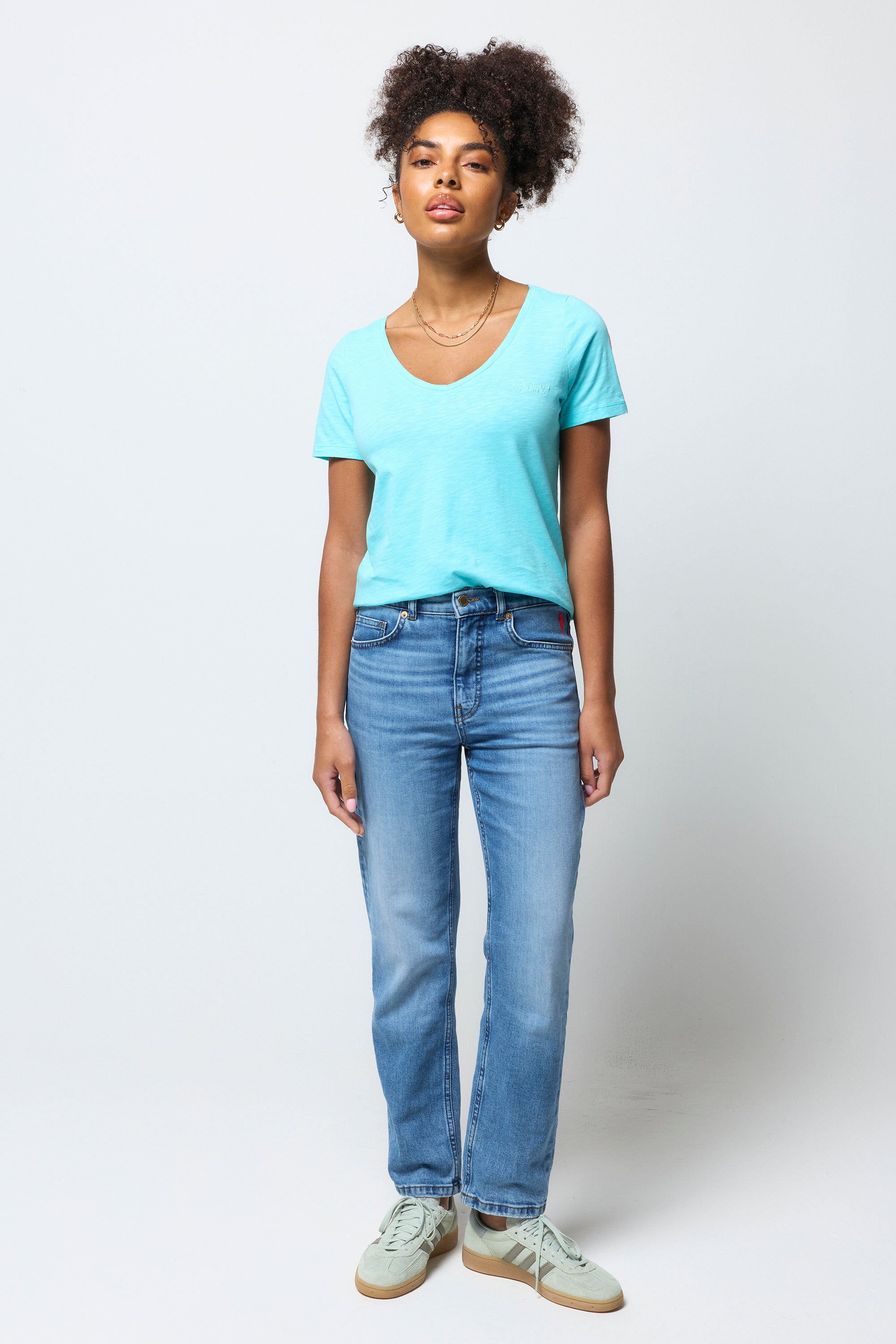 Scamp and Dude Turquoise V-Neck T-Shirt | Model wearing a turquoise v-neck t-shirt with a pair of blue boyfriend jeans and trainers.