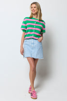 Scamp and Dude Ice Blue Wash Denim Mini Skirt | Model wearing a pink and green strip cardigan with a ice blue denim mini skirt.