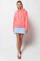 Scamp & Dude Neon Coral Washed Ultimate Hoodie | Model wearing a coral hoodie with blue denim mini skirt.