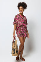 Scamp & Dude Neutral Paradise Cheetah Shorts | Model wearing a neutral paradise cheetah print shirt and shirts holding a straw bag.