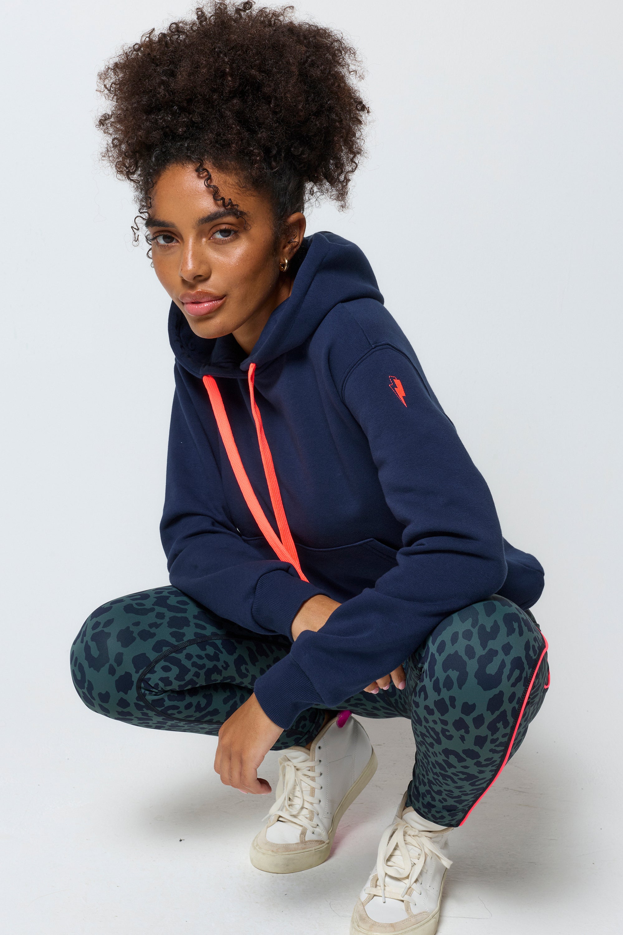 Scamp and Dude Navy Embroidered Logo Ultimate Hoodie | Model wearing dark navy hoodie with embroidered Scamp & Dude logo on the back. Worn with khaki leopard print leggings.