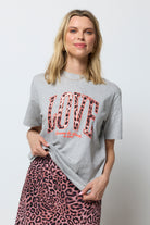 Scamp and Dude Grey Marl Love Cheetah T-Shirt | Model wearing a neutral leopard ray print skirt with a grey t-shirt featuring love cheetah print.