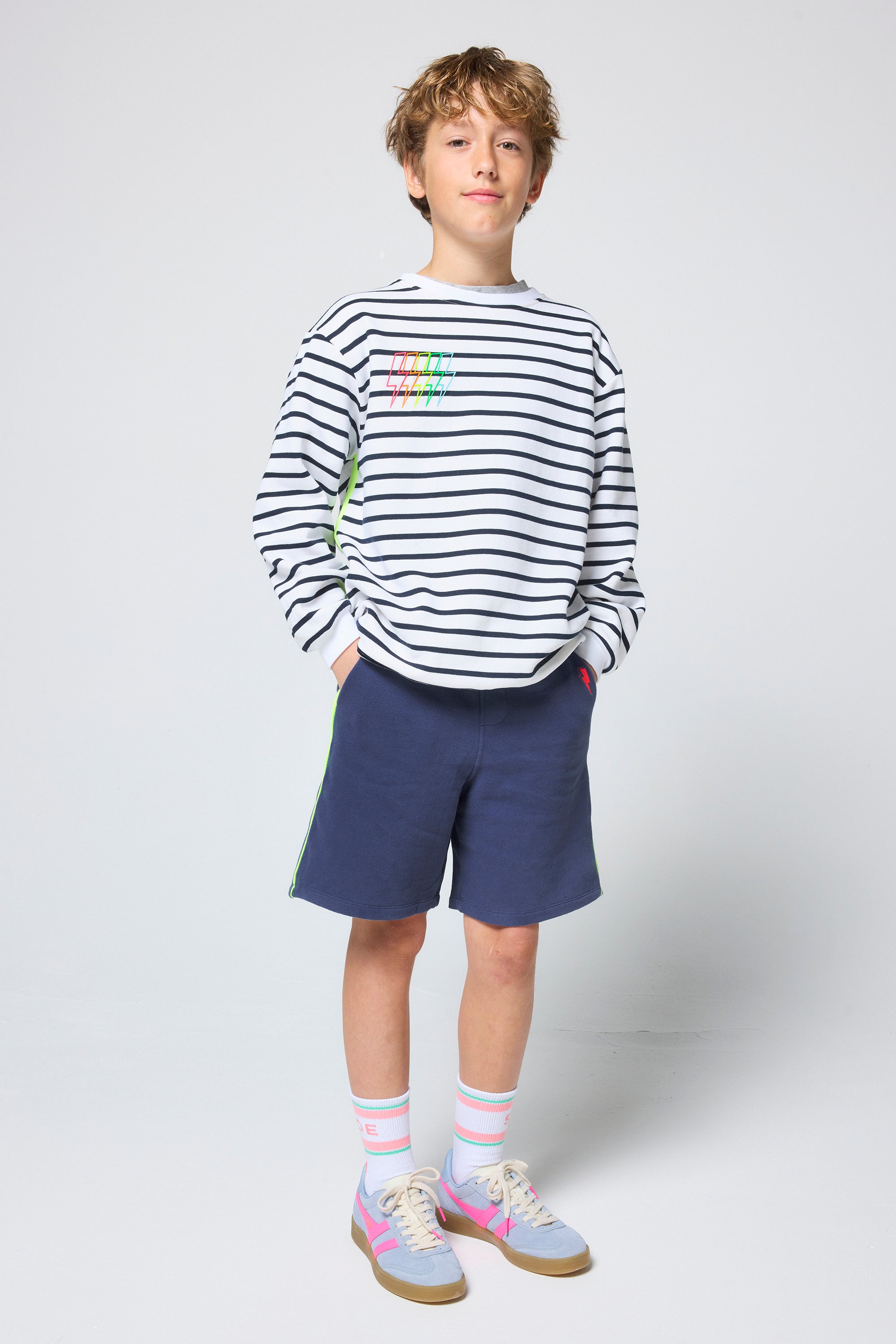 Scamp & Dude Kids Navy Stripe Colourblock Sweatshirt | Model wearing a stripe colourblock sweatshirt with blue shorts and blue trainers.