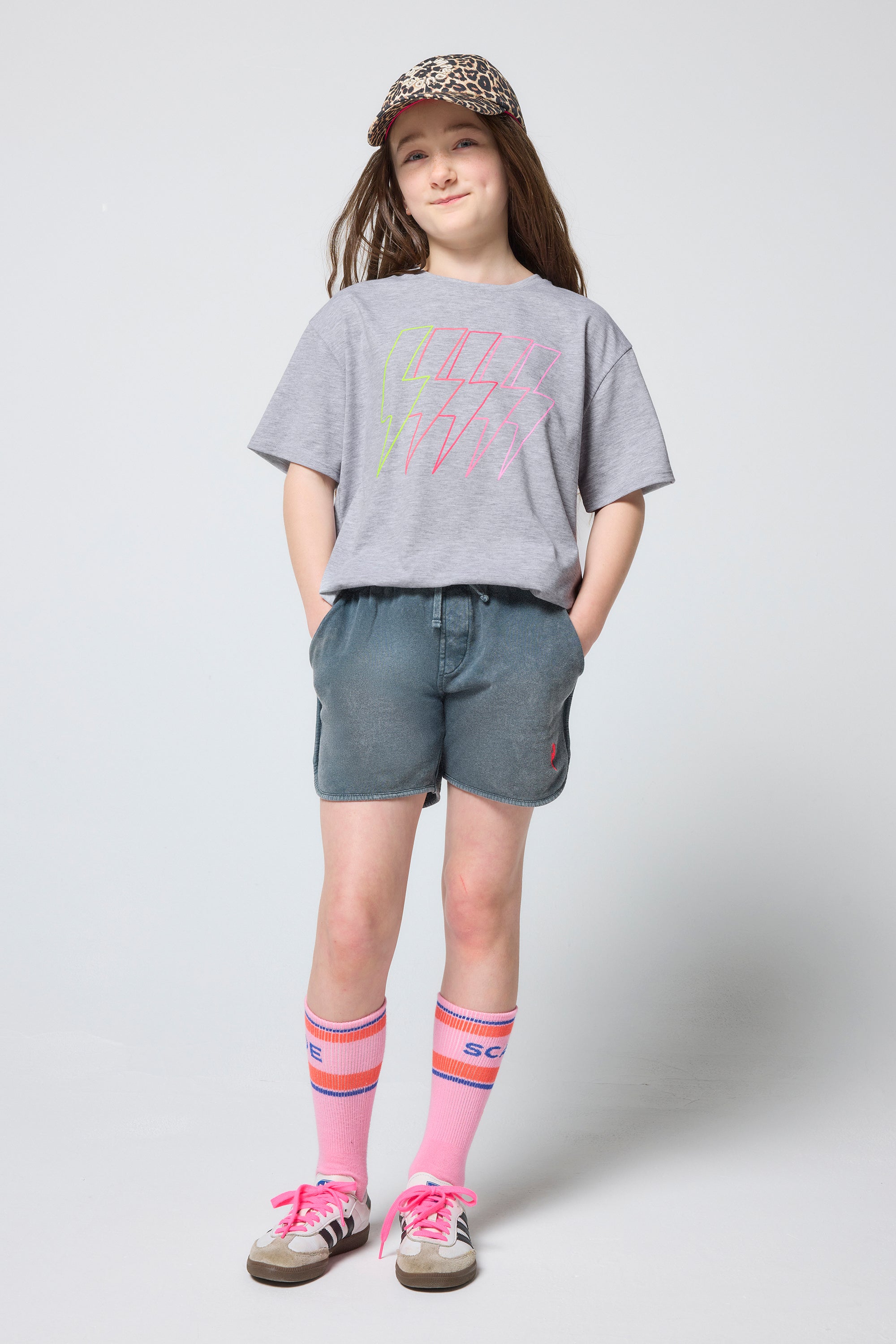 Scamp & Dude Kids Grey Marl Multi Neon Bolt T-Shirt | Model wearing a grey t-shirt, shorts, and trainers with colourful socks on a white background.