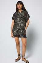 Scamp & Dude Khaki Cheetah Frill Sleeve Shirt | Model wearing a khaki cheetah print shirt with matching shorts and black sandals.