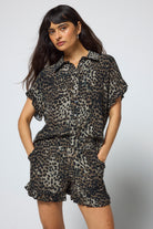Scamp & Dude Khaki Cheetah Frill Hem Shorts | Model wearing a pair of khaki cheetah print shorts with matching shirt and black sandals.