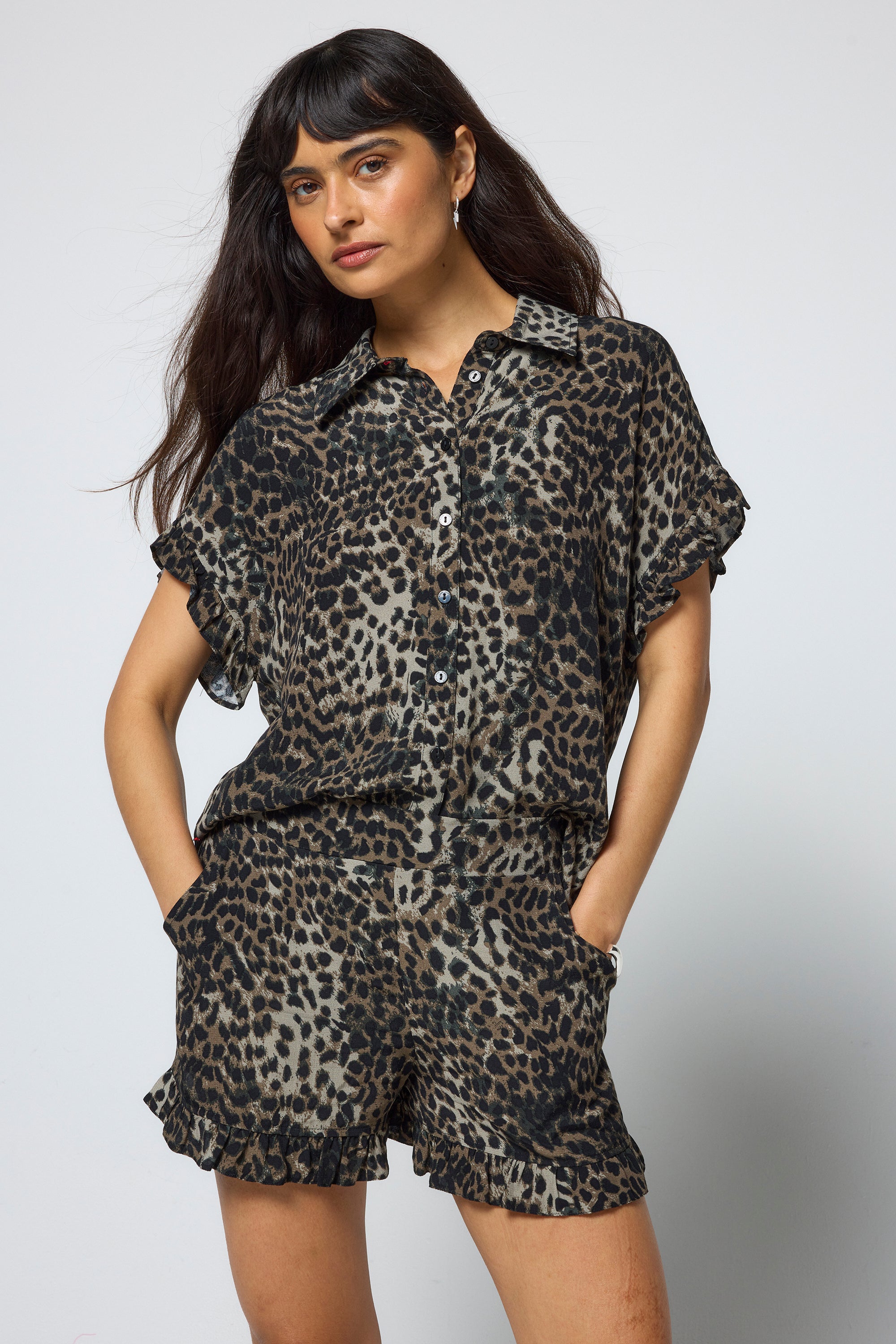 Scamp & Dude Khaki Cheetah Frill Hem Shorts | Model wearing a pair of khaki cheetah print shorts with matching shirt and black sandals.