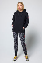 Scamp & Dude Black Multi Neon Bolt Longline Hoodie | Model wearing a black hoodie and patterned leggings on a white background.