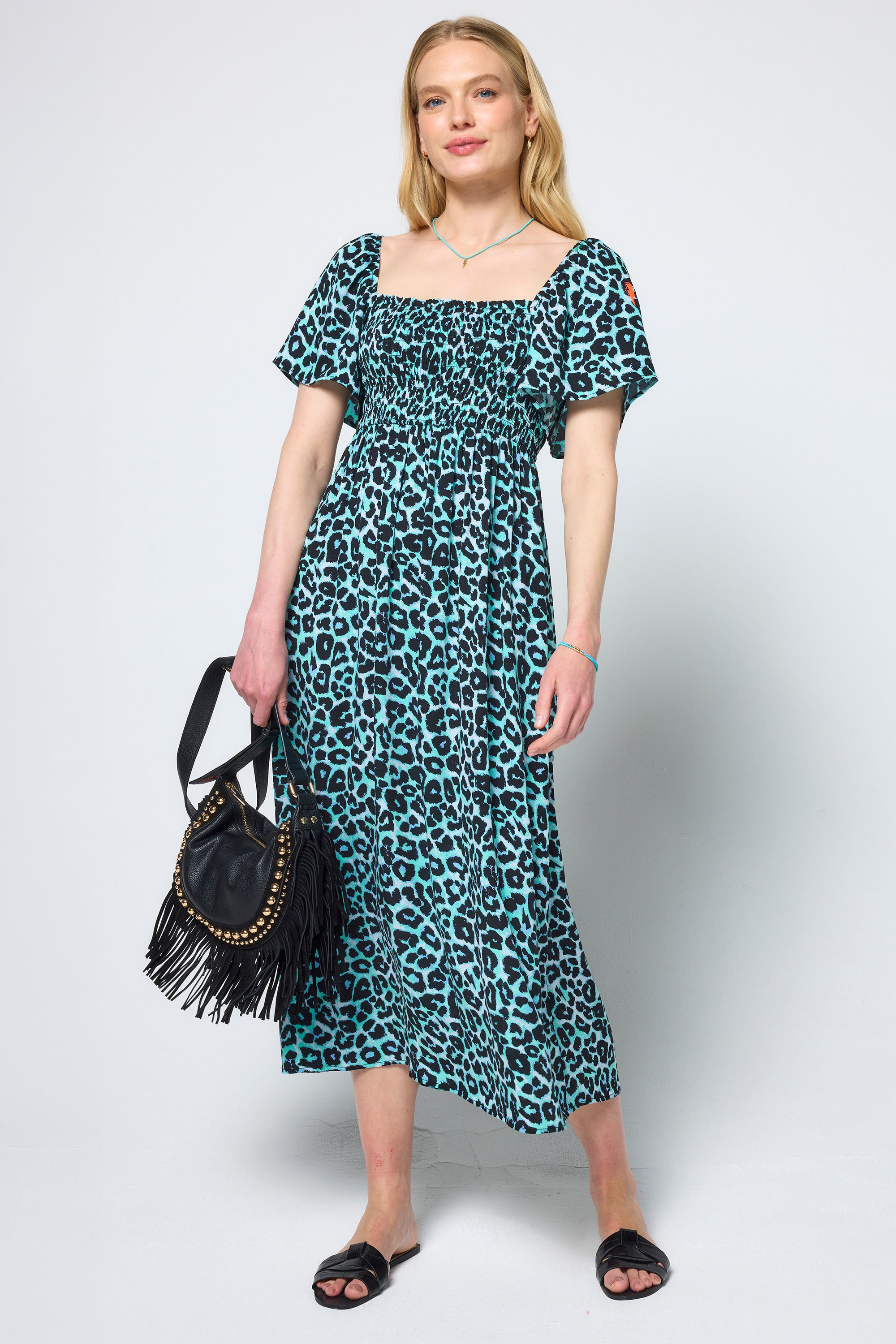 Scamp & Dude Mint Jaguar Shirred Square Neck Midi Dress | Model wearing a mint jaguar print dress holding a black handbag on a white background.