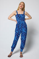 Scamp & Dude Blue Paradise Cheetah Jersey Jumpsuit | Model wearing a blue cheetah and floral printed jumpsuit with black sandals.