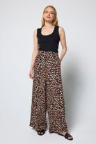 Scamp & Dude Neutral Jaguar Wide Leg Trousers | Model wearing a black tank top and jaguar print wide leg trousers on a white background.