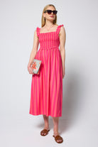 Scamp & Dude Pink and Coral Stripe Corset Sundress | Model wearing a pink and coral stripe corset dress holding a beaded stripe bag.