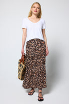 Scamp and Dude Neutral Jaguar Tiered Midi Skirt | Model wearing a neutral jaguar midi skirt with a white v-neck t-shirt and straw bag.