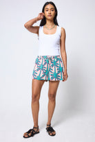 Scamp & Dude Cream with Green Shadow Palm Shorts | Model wearing a white tank top and palm print shorts on a white background.