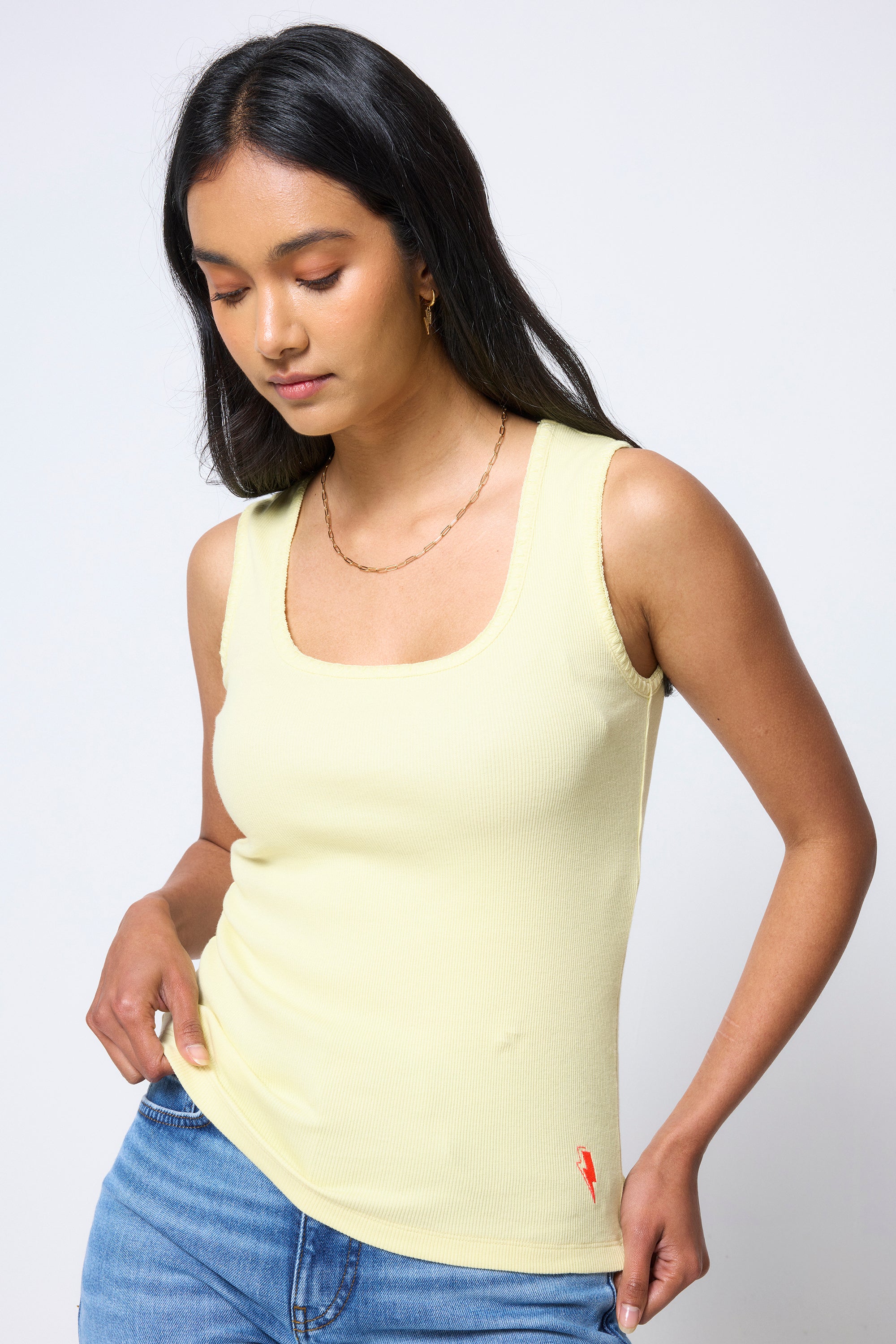 Scamp & Dude Lemon Jersey Stitch Detail Vest Top | Model wearing a light yellow tank top and blue jeans against a white background.