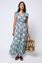 Scamp & Dude Cream with Green Shadow Palm Broderie Sleeve Pintuck Maxi Dress | Model wearing a palm tree patterned dress holding a woven bag.