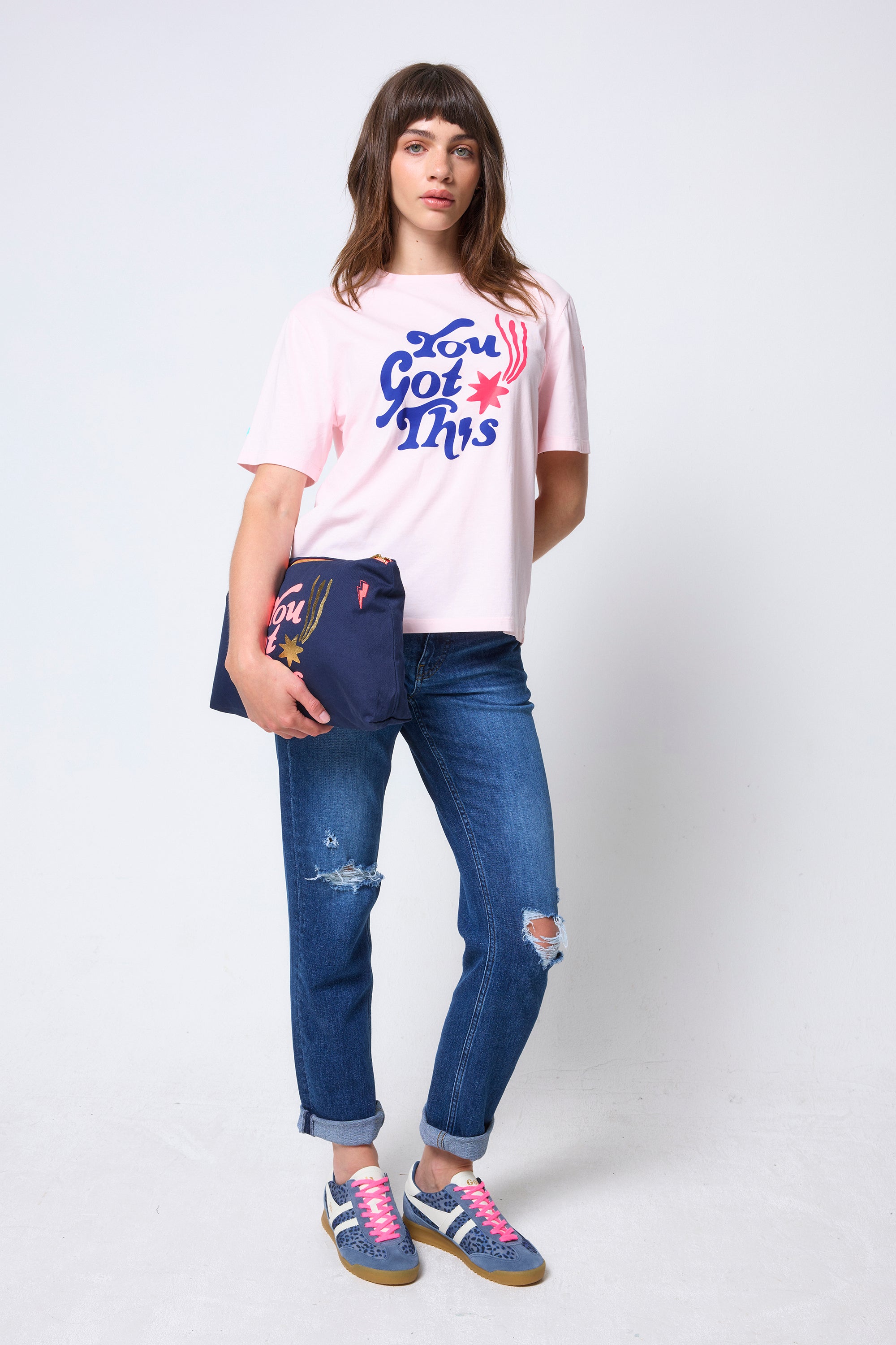 Scamp & Dude Scamp & Dude x Maggie's Pink 'You Got This!' Charity T-Shirt | Model wearing a pink t-shirt with you got this graphic print, blue jeans, and colourful trainers.