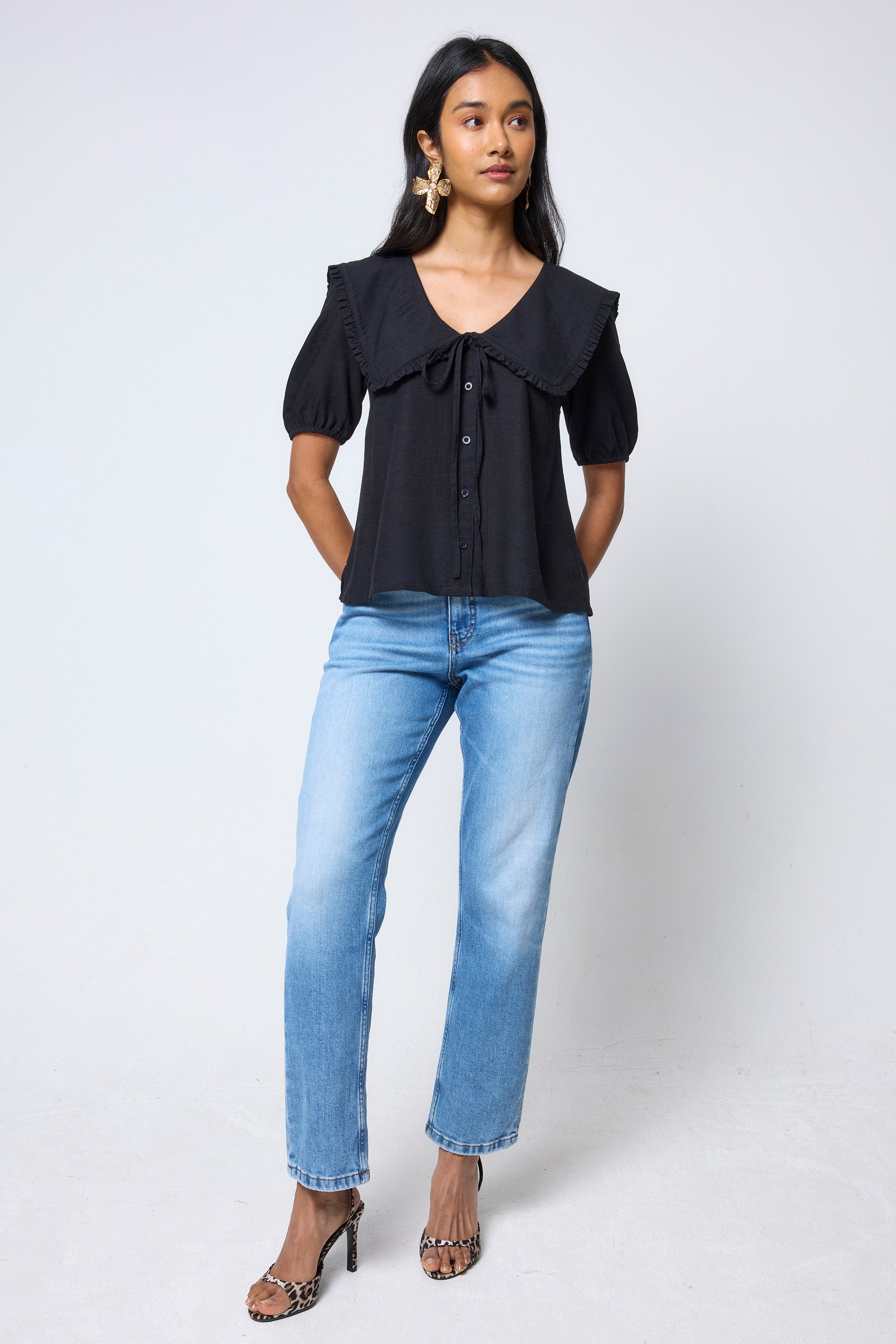 Scamp & Dude Black Collared Short Sleeve Blouse | Model wearing a black collared blouse and blue jeans with leopard print high heels.
