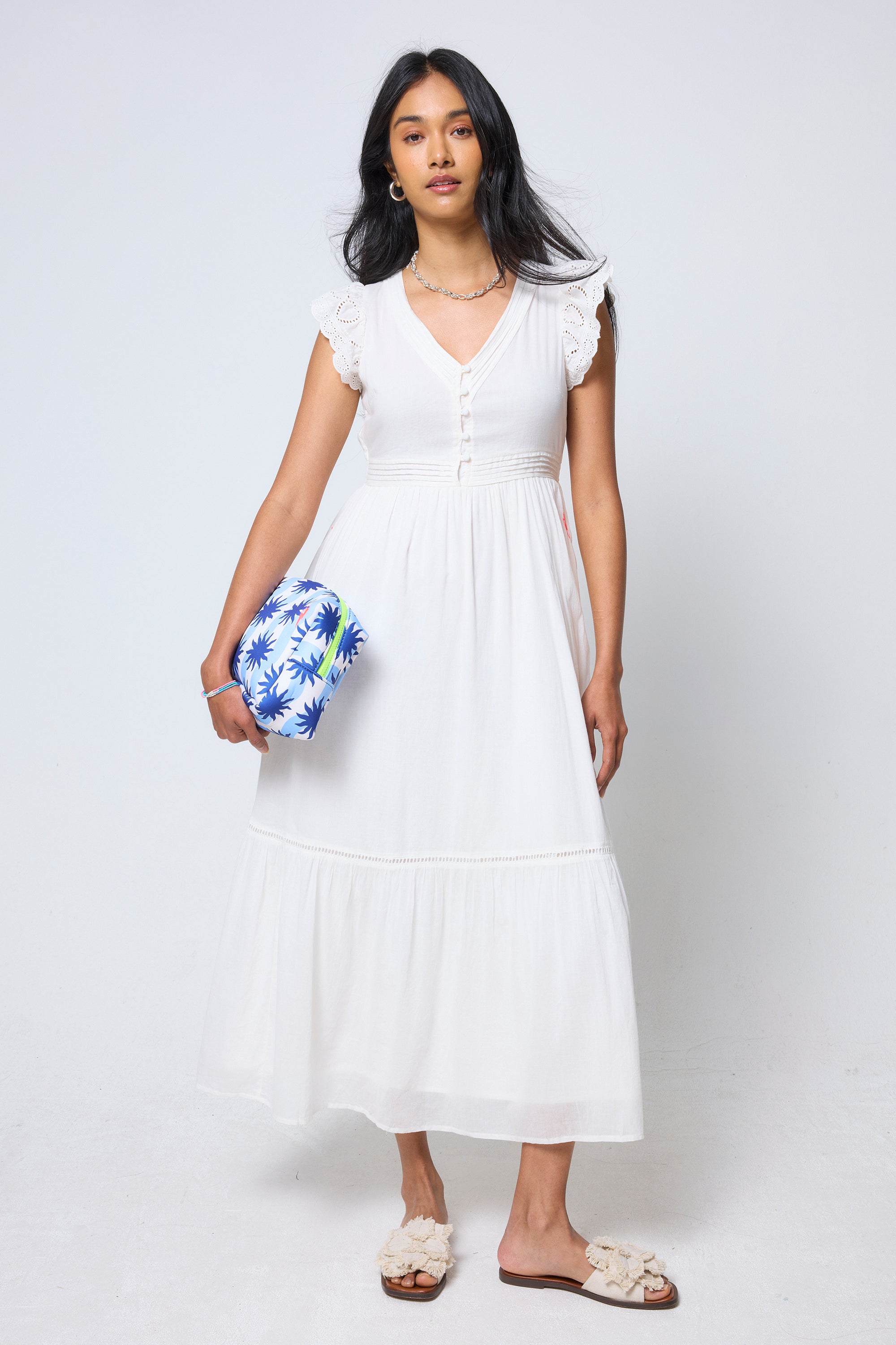 Scamp & Dude Cream Broderie Sleeve Pintuck Midi Dress | Model wearing a white pintuck midi dress holding a sunstar clutch with cream sandals.