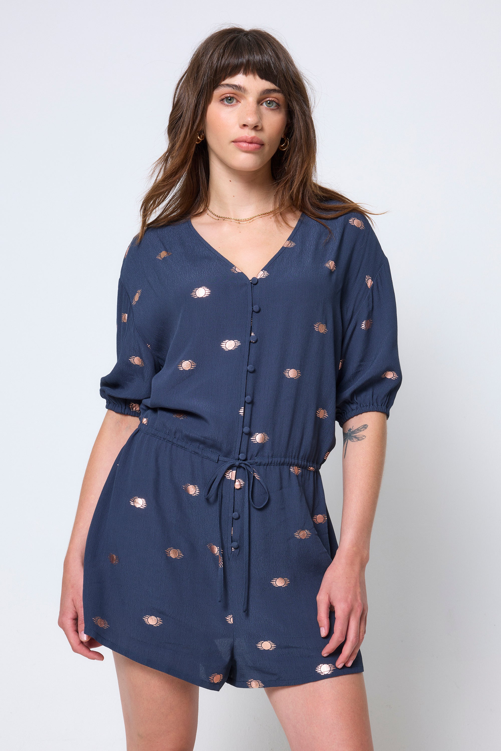 Scamp & Dude Navy with Gold Foil Playsuit | Model wearing a navy blue playsuit with a gold foil print and tie waist detail.