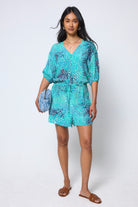 Scamp & Dude Blue Ocean Scales Playsuit | Model wearing a blue patterned playsuit, holding a denim quilted bolt bag.