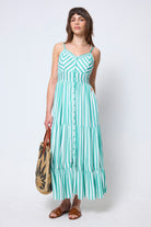 Scamp & Dude Green and White Stripe Pintuck Midi Sundress | Model wearing a green and white striped dress holding a woven bag on a white background.