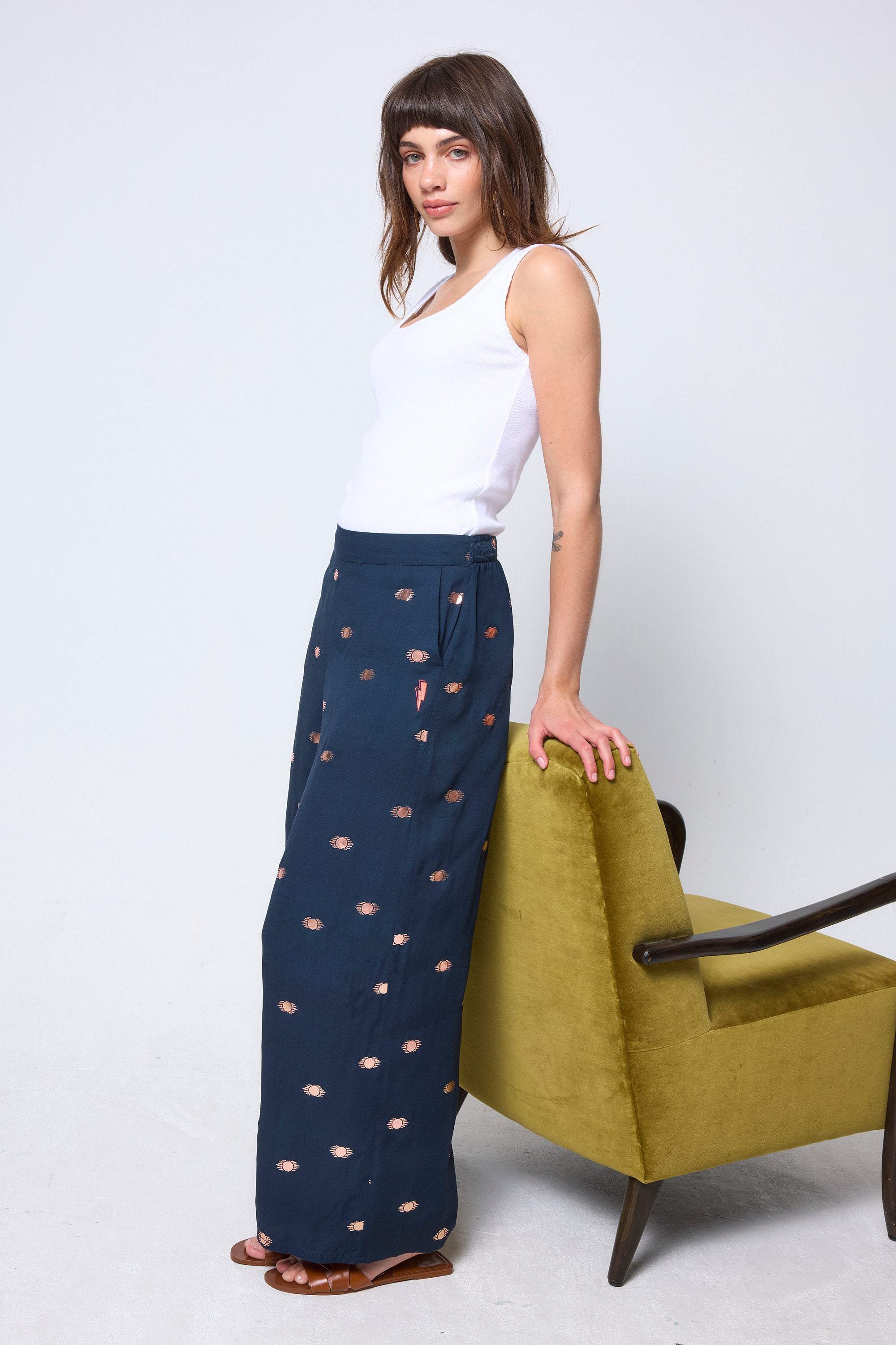 Scamp & Dude Navy with Gold Foil Wide Leg Trousers | Model wearing navy wide leg trousers with gold foil print. Worn with a white vest top.