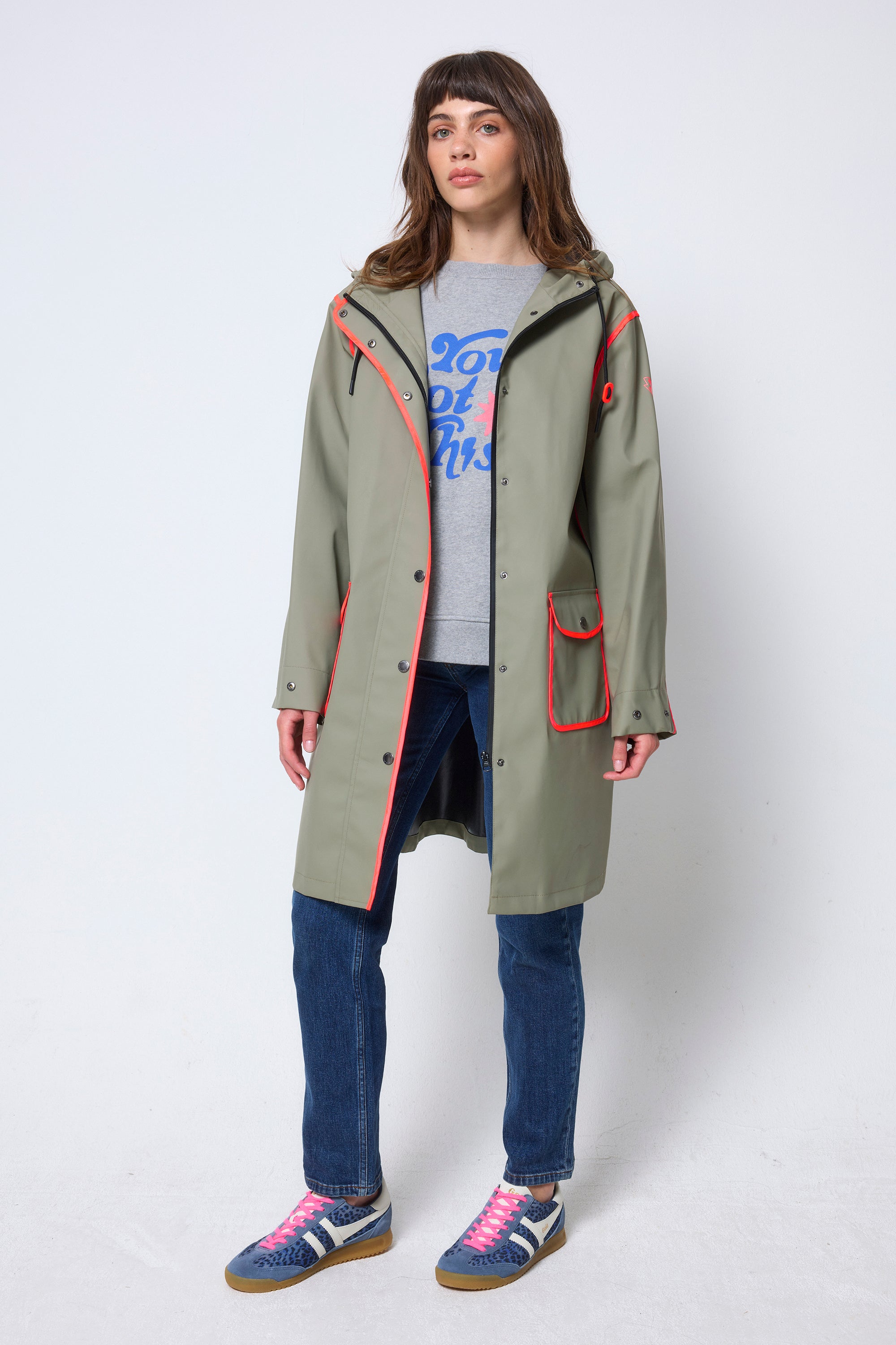 Scamp & Dude Khaki Raincoat | Model wearing a long green raincoat with neon coral details.